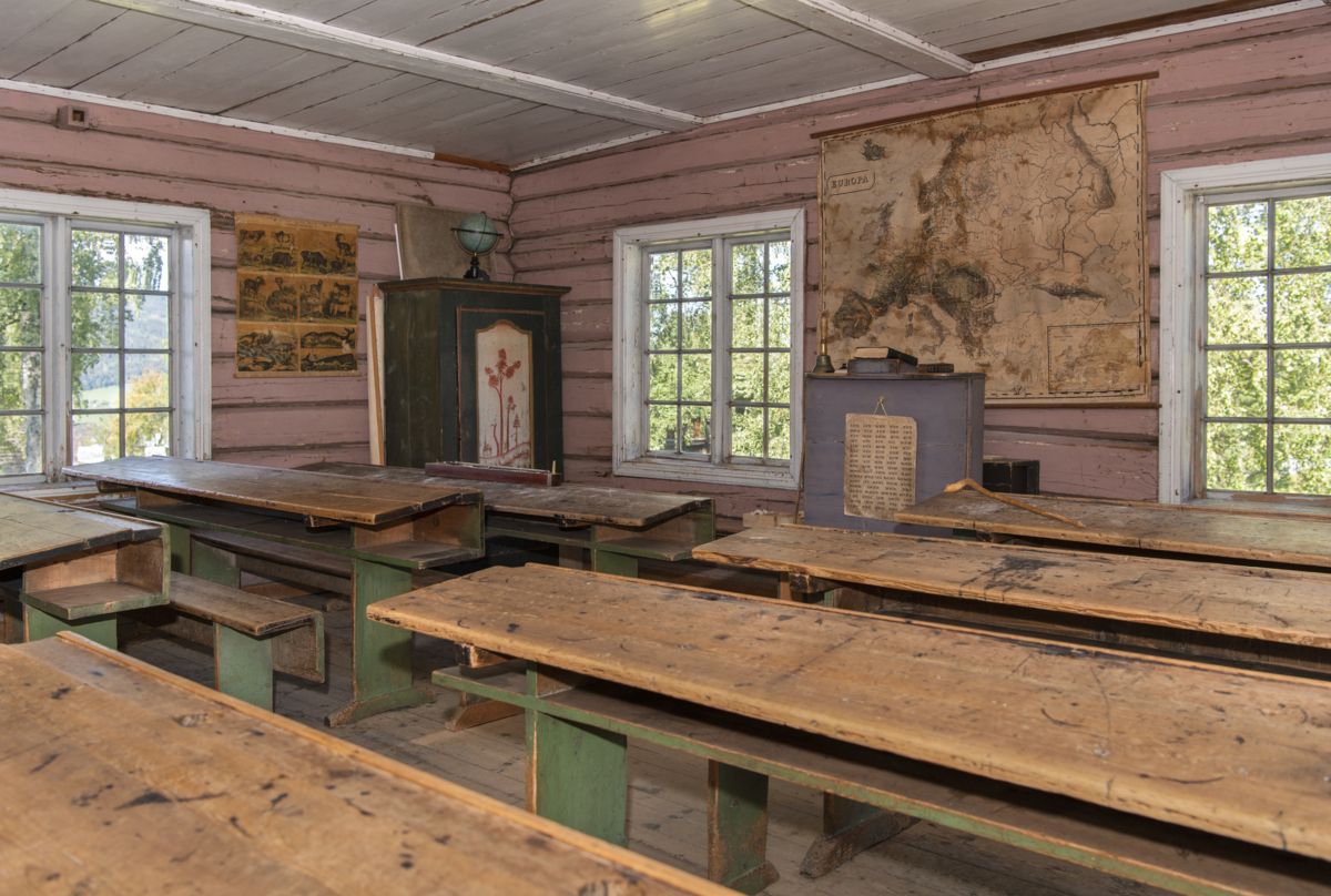 Inside the schoolhouse with a teacher's desk and benches. Photo: Tone Iren Eggen T&oslash;mte/Maihaugen.


