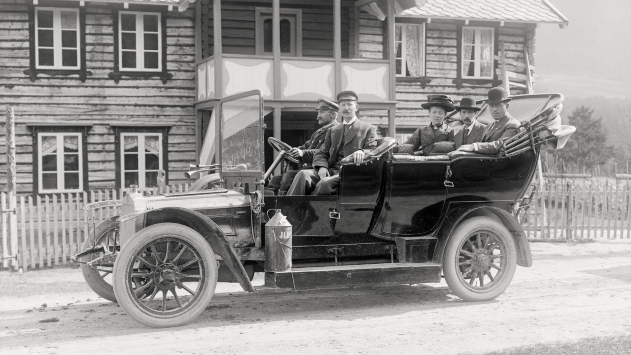 Historisk foto av en gammeldags bil med fem personer i.